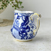 Three-quarter view of Royal Crown Derby Blue Mikado creamer showing the curved handle, pouring spout, blue decoration, and gold trim.
