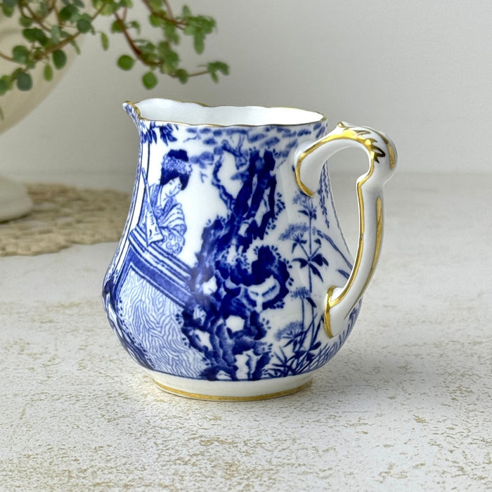 Three-quarter view of Royal Crown Derby Blue Mikado creamer showing the curved handle, pouring spout, blue decoration, and gold trim.