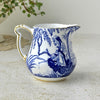 Back view of Royal Crown Derby creamer showing blue landscape decoration wrapping around the small white porcelain jug.