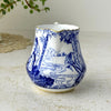 Spout-side view of Blue Mikado creamer with cobalt blue figures, landscape decoration, and gold-trimmed scalloped rim.