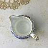Top-down view of Royal Crown Derby creamer showing the white interior, pouring spout, curved handle, and gold-trimmed rim.