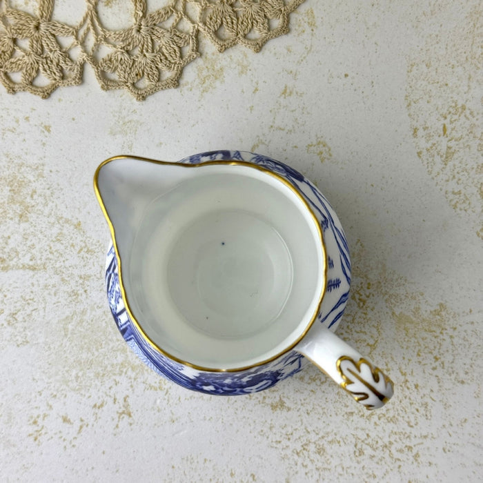 Top-down view of Royal Crown Derby creamer showing the white interior, pouring spout, curved handle, and gold-trimmed rim.