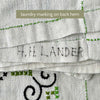Back hem of the ecru embroidered tablecloth showing a faded handwritten laundry marking in dark ink.