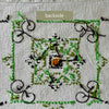 Backside of an embroidered medallion showing the reverse stitching and numerous loose thread ends in green and navy.