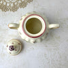 Overhead view of open sugar bowl with lid removed, showing the cream-colored interior and floral decoration on the lid.