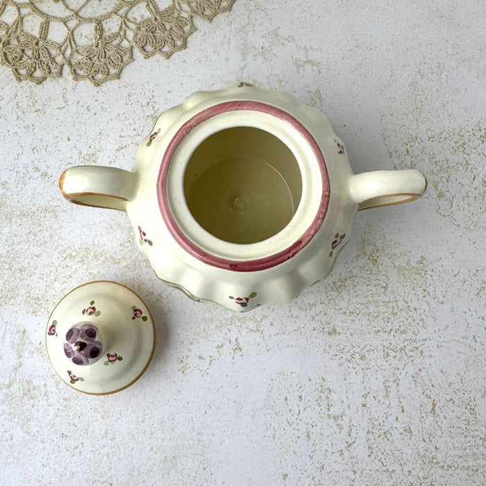 Overhead view of open sugar bowl with lid removed, showing the cream-colored interior and floral decoration on the lid.