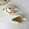 Overhead view of the matching sugar bowl and creamer showing their openings, curved handles, and painted floral decoration.