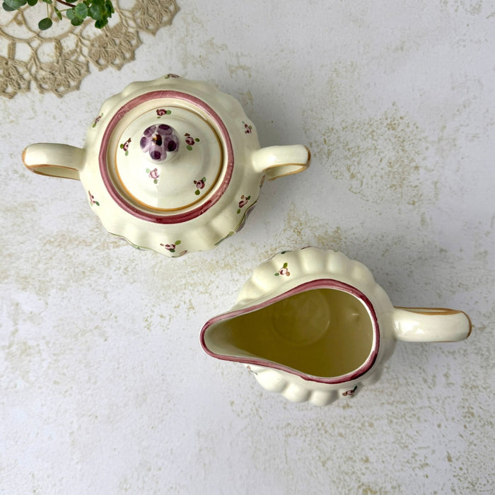 Overhead view of the matching sugar bowl and creamer showing their openings, curved handles, and painted floral decoration.