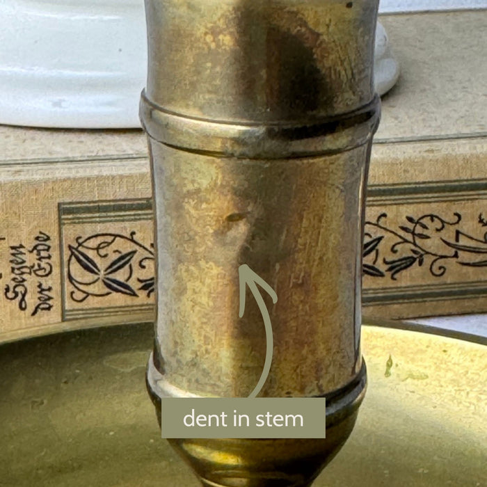 Close-up of the brass chamberstick stem with an arrow identifying a small dent in the metal.