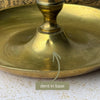 Close-up of the brass chamberstick base with an arrow identifying a small dent near the central stem.