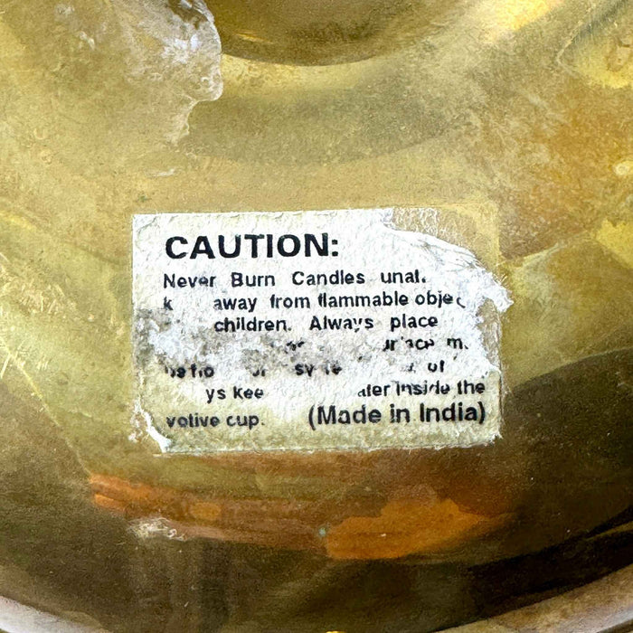 Close-up of the worn original paper safety label on the underside of the brass chamberstick, including the words Made in India.