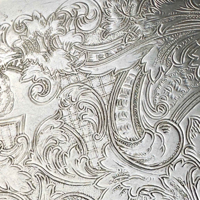 Close-up of the tray's embossed decoration showing scrolling foliage, curved ornamental bands, and finely textured areas.