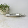 Low side view of the silverplate tray showing its shallow profile and slightly elevated ornamental rim.