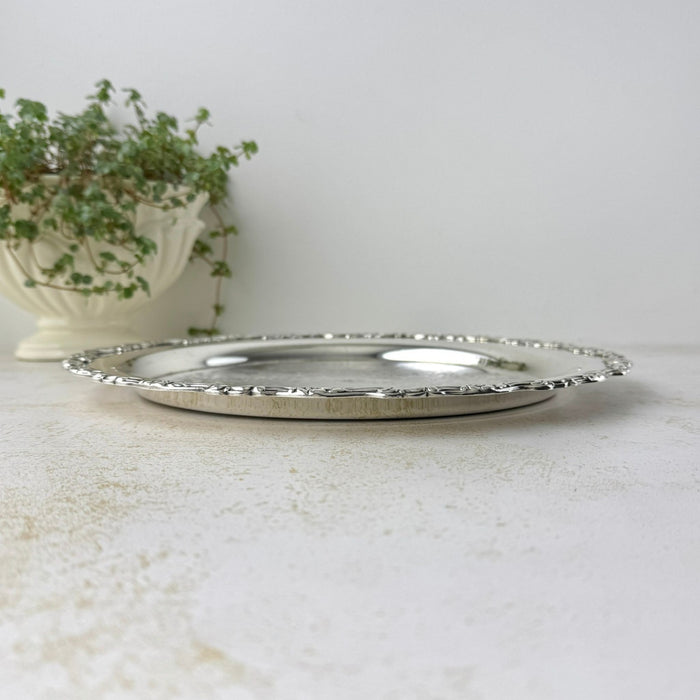 Low side view of the silverplate tray showing its shallow profile and slightly elevated ornamental rim.