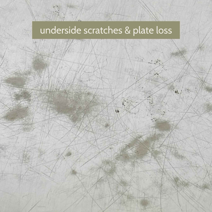 Close-up of the tray's underside showing extensive scratches and scattered areas of silverplate loss revealing darker underlying metal.