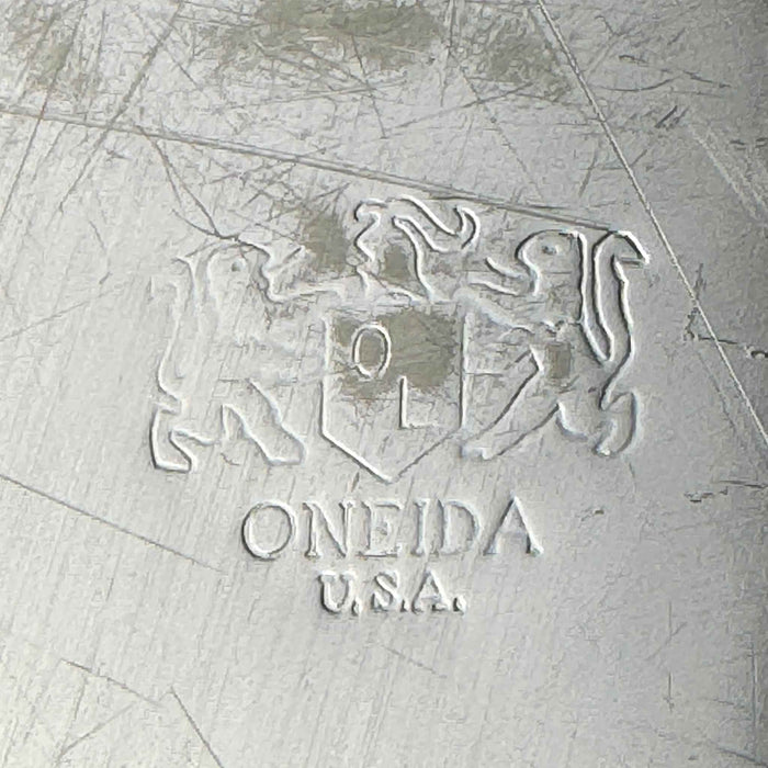 Close-up of the Oneida U.S.A. maker's mark with an OL shield and animal figures stamped into the scratched underside of the tray.