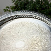 Close-up of the tray's rolled decorative rim, pierced vertical gallery openings, and finely detailed floral scrollwork on the silver surface.