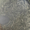Close-up of embossed roses, curling leaves, crosshatched textures, and ornamental scrolls decorating the tray's base.