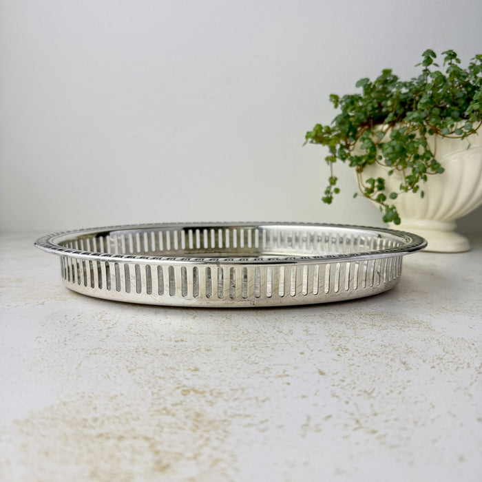 Low side view showing the oval tray's shallow base, tall pierced gallery railing, and raised patterned rim.