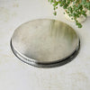 Underside of the oval silverplate tray showing a plain metal base with scattered fine scratches and the decorative rim around the edge.
