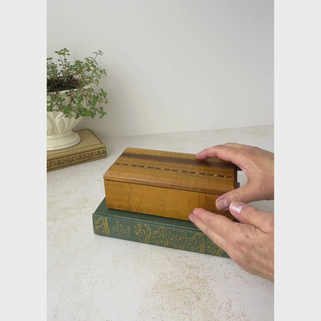 Vintage wooden box with inlaid band is opened and tilted to show the interior, and the top of the box is displayed close-up
