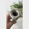 Vintage silver-colored brass bud vase rotated by hand to show the engraved floral decoration, narrow flared neck, and round footed base.