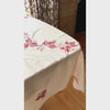 Video of cream vintage tablecloth with burgundy and coral embroidered leaves and taupe scalloped edging shown on a rectangular dining table.