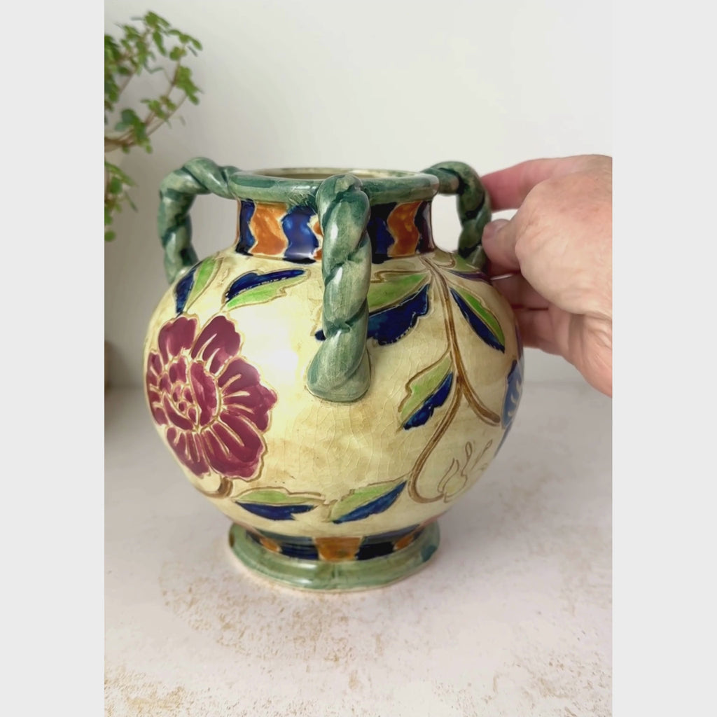 Vintage Maruhon Ware vase rotated on a neutral backdrop, rotated by one handle to show the navy blue floral side