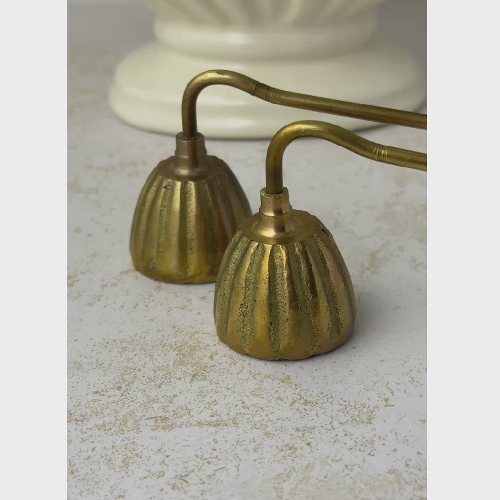 Pair of vintage brass candle snuffers shown from ribbed bell-shaped heads along the long twisted handles to the ball handle ends
