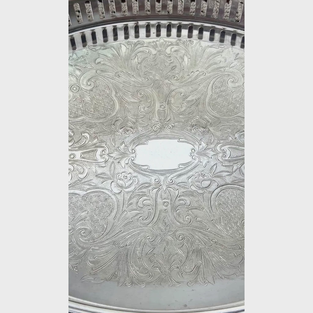 Closeup video of vintage oval silverplate gallery tray with a pierced railing, patterned raised rim, and elaborate floral scrollwork across the base.