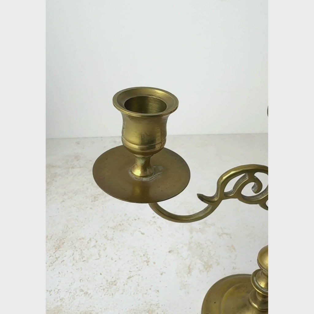 Close view of a vintage three arm candelabra, panning across the candle cups and stem before pulling back to show the full candelabra