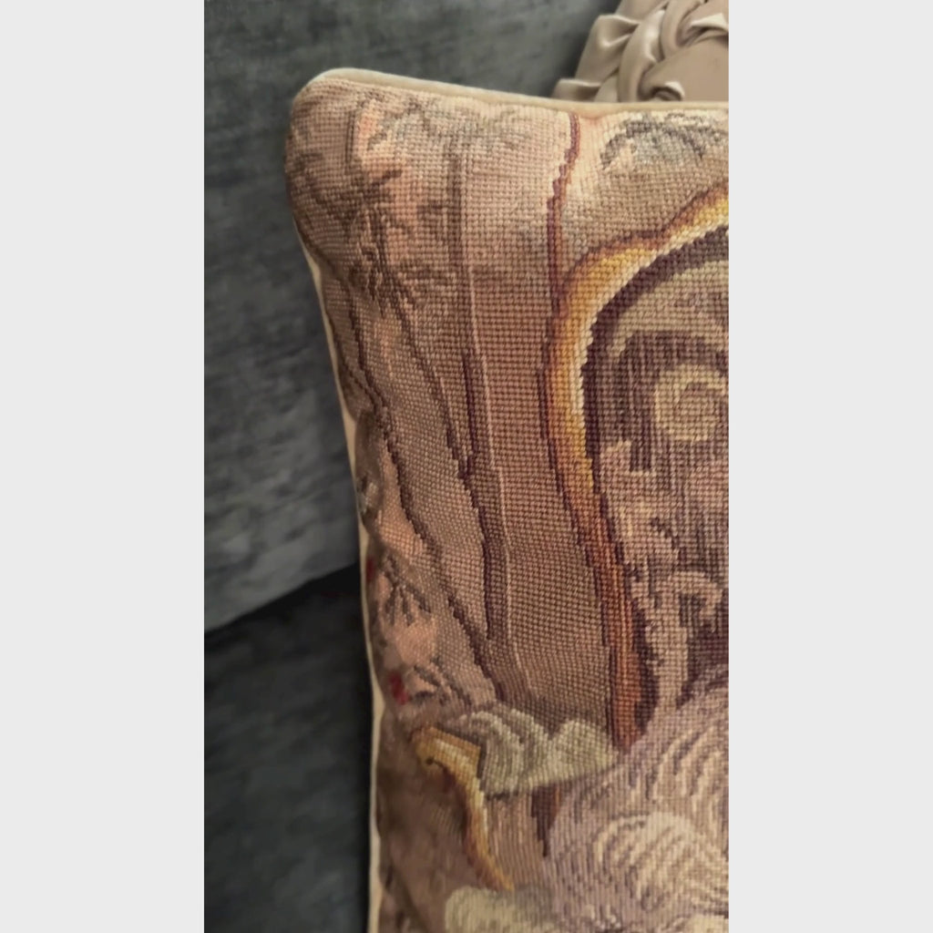 Close-up video of square wool needlepoint pillow depicting a white Westie seated on an ornate armchair, surrounded by warm olive, gold, pink, plum, and tan details.