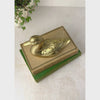 Vintage brass duck figurine shown from above, with the camera panning down to a straight-on view of the duck’s full profile