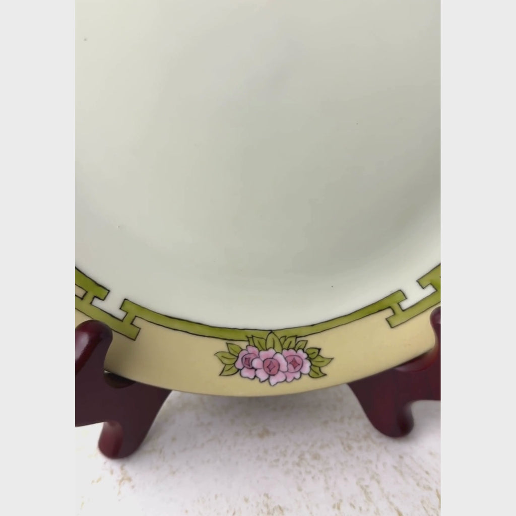 Close view of antique plate, panning around the hand-painted border before pulling back to show the full plate on a plate stand