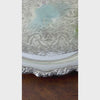 Closeup video of round silverplate serving tray with an ornate scalloped floral border and intricate scrolling decoration across the center