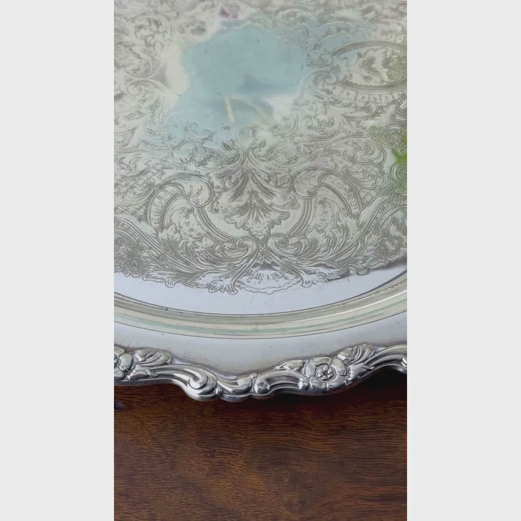 Closeup video of round silverplate serving tray with an ornate scalloped floral border and intricate scrolling decoration across the center