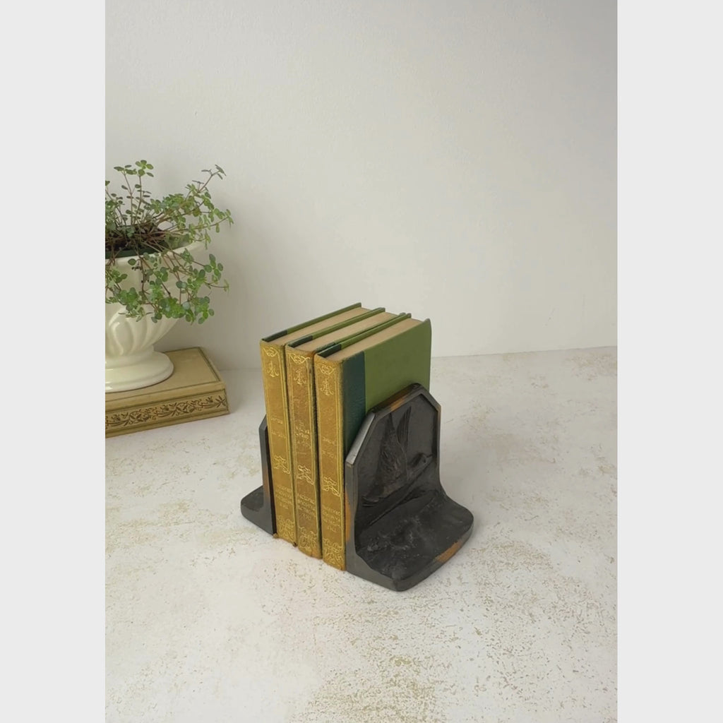 Vintage cast iron duck bookends shown holding antique books, one bookend is picked up to show a closer view of the front then turned to show the back