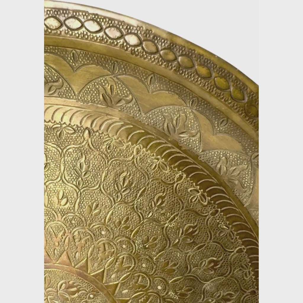 Vintage round brass tray panning the decorative surface close up along the rim and then to the center of the tray
