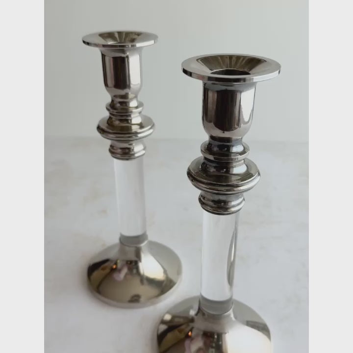 Short video of silver lucite candle holders being picked up and turned to show its shape, finish, and details in natural light