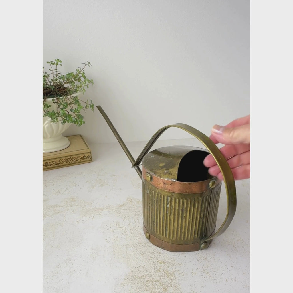 Vintage brass indoor watering can with copper accents is shown against a neutral backdrop as it is rotated to display the front, back, top, and underside