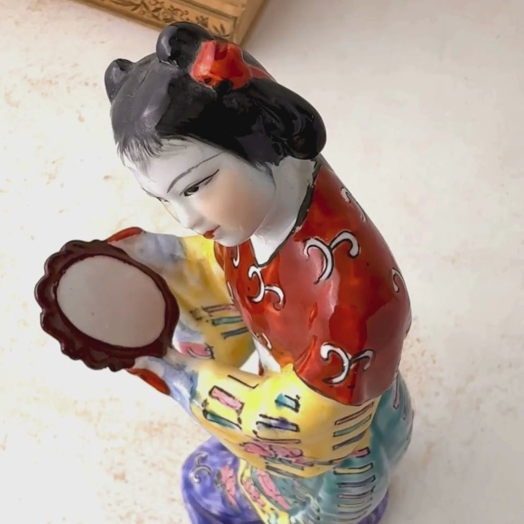 Vintage famille rose porcelain court lady figurine close up of her profile gazing towards her mirror and panning around to a view of her face