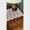 Video of white crochet table runner styled across a wood sideboard with brass candlesticks and a white planter, showing the medallion pattern and scalloped edge.