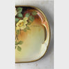 Overhead view of antique porcelain tray shown from the right handle and S. Nadesco signature across the hand-painted florals and gold trim to the left handle.