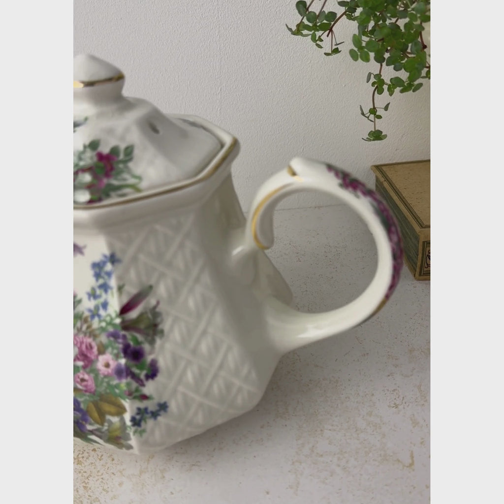 Vintage Sadler Windsor teapot with multicolor floral decoration, embossed basket-weave sides, and gold trim styled with trailing plant shown from a handle close-up to pulling back to reveal the entire teapot