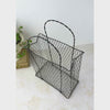 Vintage wire basket with paper bag form shown on a neutral backdrop, panning from overhead to the basket front