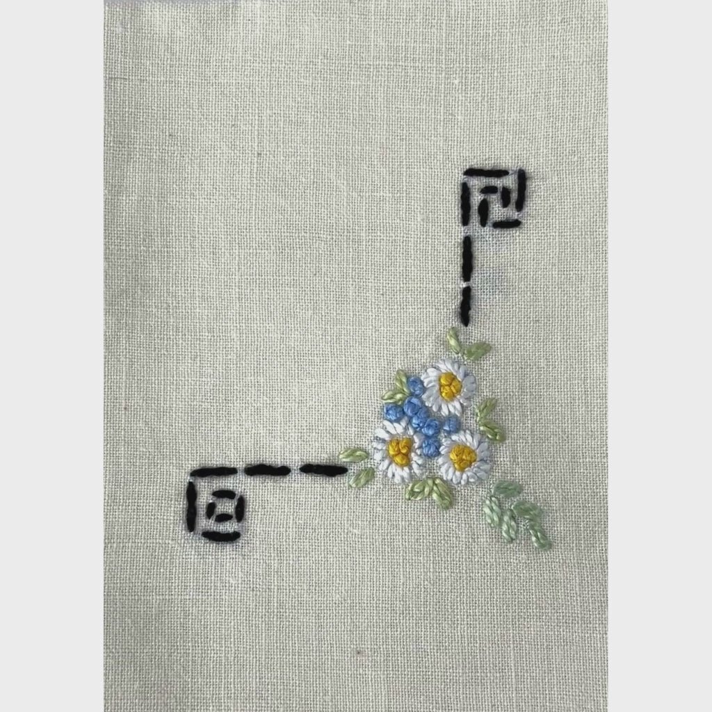 Vintage linen cocktail napkins, close-up panning acoss floral and black geometric hand embroidery and crochet edging