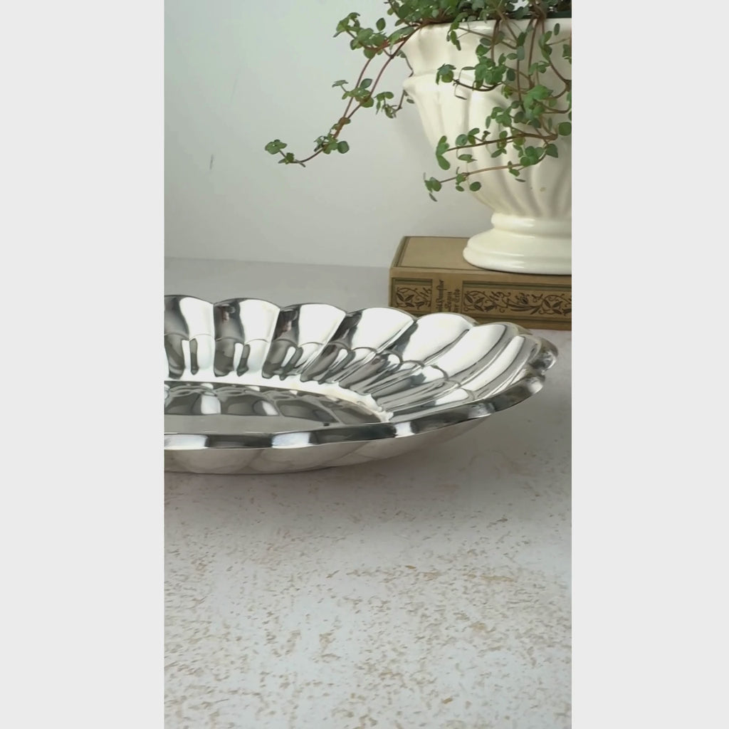 Close-up view of vintage Towle oval silverplate bread tray from a low angle along the front and then shifting to an overhead view. 