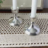 Close-up video of pair of polished sterling silver Duchin candlesticks with wide circular bases and cup-shaped candle sockets on a crochet surface.
